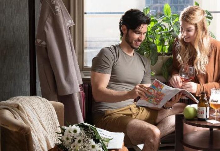 Couple at gay-friendly The Three Corners Hotel Art Superior, Budapest. Man reads a magazine, woman drinks wine. Travel guide for gay men.