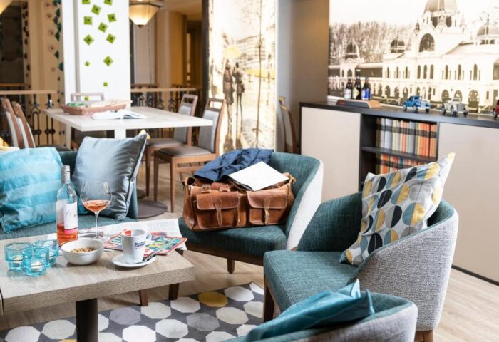 The Three Corners Hotel Art Superior: Gay-friendly hotel lounge area with wine, snacks, and a leather bag. A relaxing space for gay travelers.