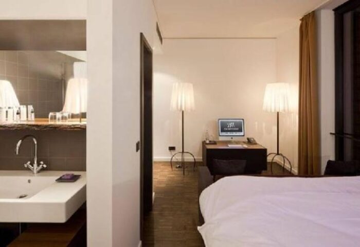 The Weinmeister Berlin-Mitte Adults Only hotel room. Gay-friendly, pet-friendly hotel. Sink, desk, lamps, and bed in modern design.