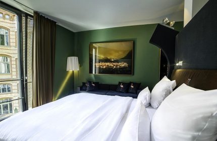 The Weinmeister Berlin-Mitte Adults Only hotel room. Gay-friendly, pet-friendly hotel with a view, bed, couch, and flamingo pillows.