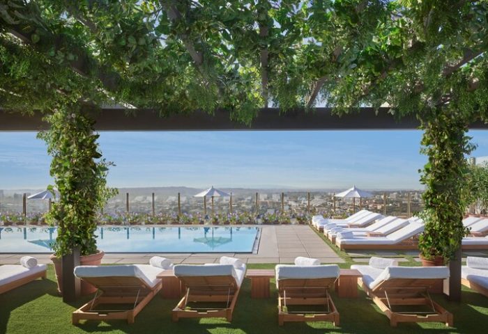 Rooftop pool at The West Hollywood EDITION, a gay-friendly hotel. Loungers, city views, and lush greenery create a relaxing, upscale vibe.