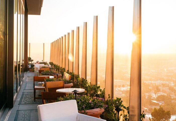 West Hollywood EDITION's gay-friendly hotel terrace. Sunset view, stylish seating, and plants create a chic, welcoming atmosphere.