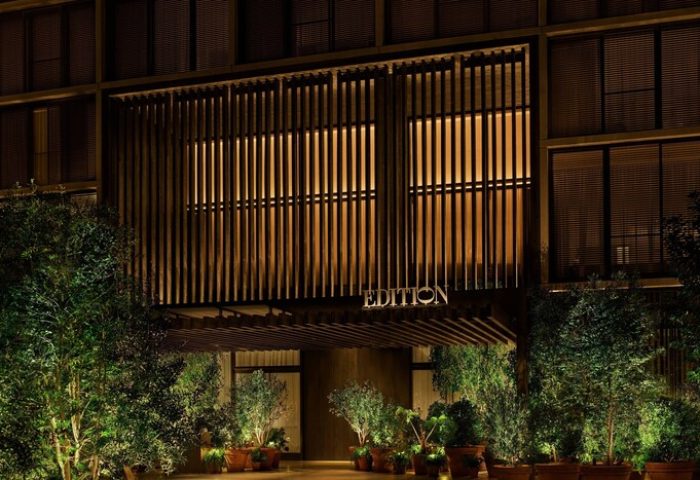 The West Hollywood EDITION hotel facade at night. Gay-friendly travel destination with modern architecture and lush greenery. Upscale and inviting.