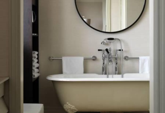 Bathroom at The Westbury Hotel, a gay-friendly hotel. Features a clawfoot tub, round mirror, and plush towels. Luxury travel for gay men.