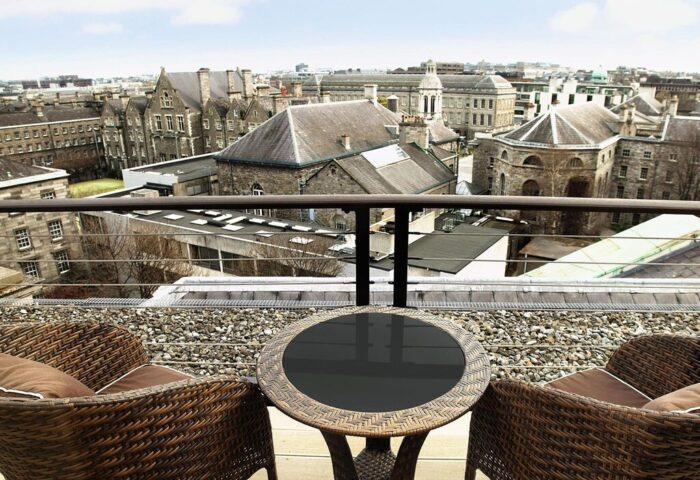 Dublin's College Green Hotel view. Balcony with table, chairs, and city skyline. Gay-friendly The Westin Dublin rooftop patio.