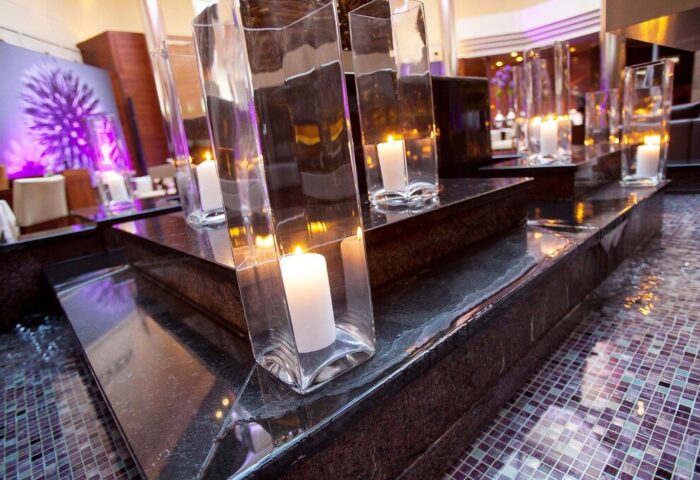Candlelit ambiance at The Westin Grand Frankfurt, a gay-friendly hotel. Glass vases hold candles, atop dark stone, creating a romantic atmosphere.