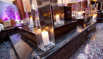 Candlelit ambiance at The Westin Grand Frankfurt, a gay-friendly hotel. Glass vases hold candles, atop dark stone, creating a romantic atmosphere.