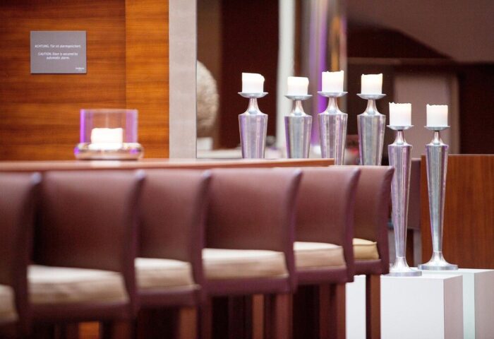 The Westin Grand Frankfurt gay-friendly hotel decor. Candles on silver stands, brown leather chairs, and wood paneling create a warm ambiance.