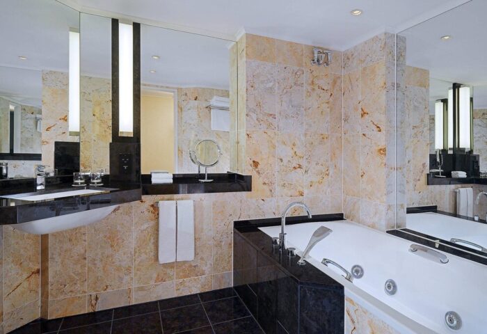 Bathroom at The Westin Grand Frankfurt, a gay-friendly hotel. Features a bathtub, marble tiles, black countertops, & modern design. Ideal for gay travel.