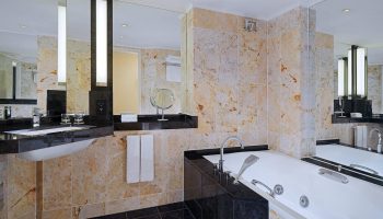 Bathroom at The Westin Grand Frankfurt, a gay-friendly hotel. Features a bathtub, marble tiles, black countertops, & modern design. Ideal for gay travel.