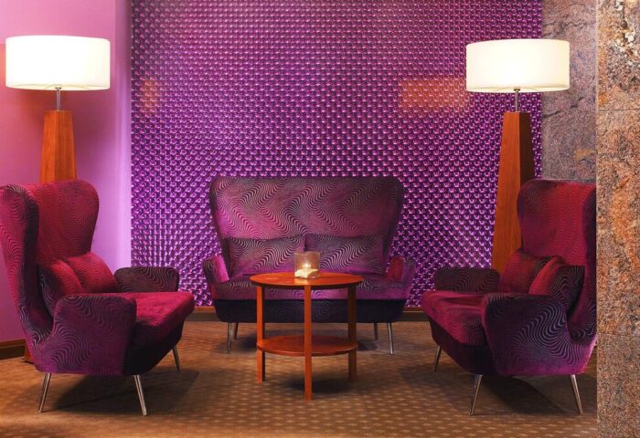 The Westin Grand Frankfurt gay-friendly hotel lounge area. Purple chairs and textured wall, lamps, and table create a stylish, modern space.