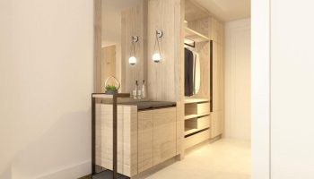 The Westin Grand Frankfurt gay-friendly hotel room. Light wood closet with drawers, hanging clothes, side table, mirror, and modern lighting.