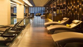 The Westin Jakarta gay-friendly hotel's pool area. Lounge chairs line the pool. Wood floors and modern decor. Great for gay travel.