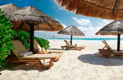 Beachfront at The Westin Lagunamar Ocean Resort Villas & Spa Cancun, a gay-friendly hotel. Lounge chairs under thatched umbrellas.