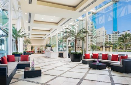 The Westin Lagunamar Ocean Resort Villas & Spa Cancun lobby. Gay-friendly hotel interior with palm trees, sofas, and glass walls.