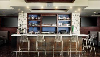 Bar area at The Westin Lagunamar Ocean Resort Villas & Spa Cancun. Gay-friendly hotel bar with stools, drinks, and TVs. Cancun travel.