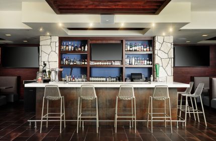 Bar area at The Westin Lagunamar Ocean Resort Villas & Spa Cancun. Gay-friendly hotel bar with stools, drinks, and TVs. Cancun travel.