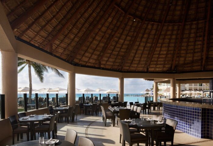 Dining area at The Westin Lagunamar Ocean Resort Villas & Spa Cancun, a gay-friendly hotel. Thatch roof and ocean view.