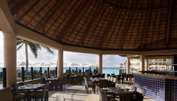 Dining area at The Westin Lagunamar Ocean Resort Villas & Spa Cancun, a gay-friendly hotel. Thatch roof and ocean view.