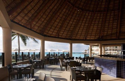 Dining area at The Westin Lagunamar Ocean Resort Villas & Spa Cancun, a gay-friendly hotel. Thatch roof and ocean view.
