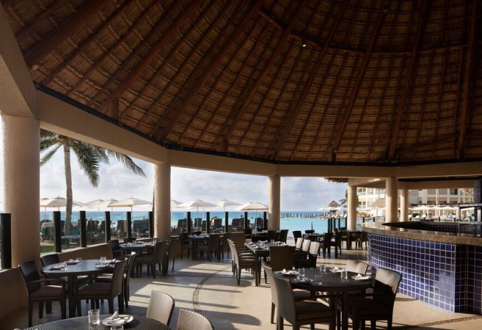 Dining area at The Westin Lagunamar Ocean Resort Villas & Spa Cancun, a gay-friendly hotel. Thatch roof and ocean view.