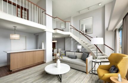 The Westin Long Beach gay-friendly hotel suite. Living room with stairs, sofa, yellow chair, and modern decor. Upscale travel for gay men.