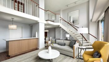 The Westin Long Beach gay-friendly hotel suite. Living room with stairs, sofa, yellow chair, and modern decor. Upscale travel for gay men.