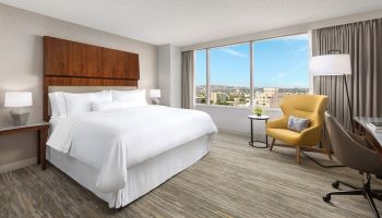 The Westin Long Beach gay-friendly hotel room. King bed, city view, yellow chair, desk. Modern, comfortable, and inviting space.