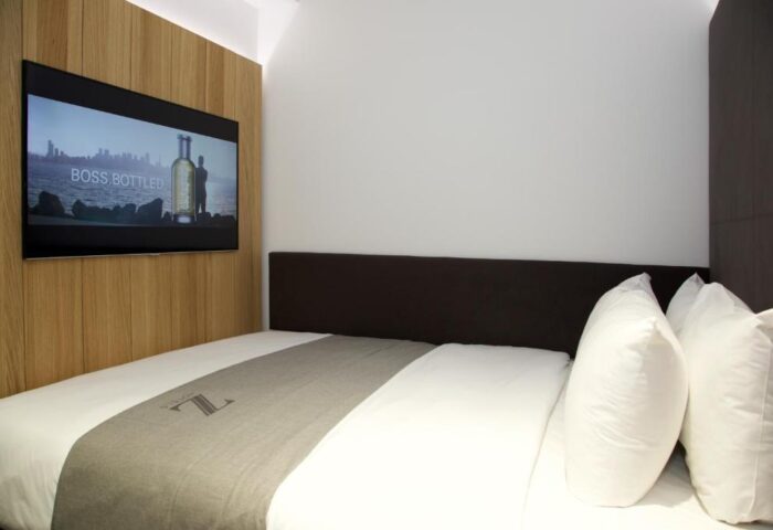 The Z Hotel City room. Gay-friendly hotel with bed, pillows, and TV showing Boss Bottled ad. Modern design for gay travelers.
