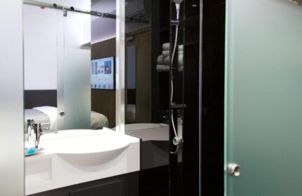 Bathroom at The Z Hotel City, a gay-friendly hotel. Features a modern sink, shower, and a view into the bedroom with a TV. Ideal for gay travelers.
