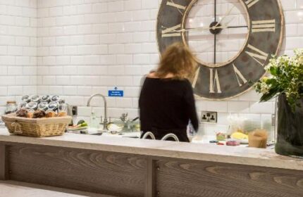 The Z Hotel City's buffet area with a large clock, pendant lights, and white brick wall. A gay-friendly hotel with modern design elements.