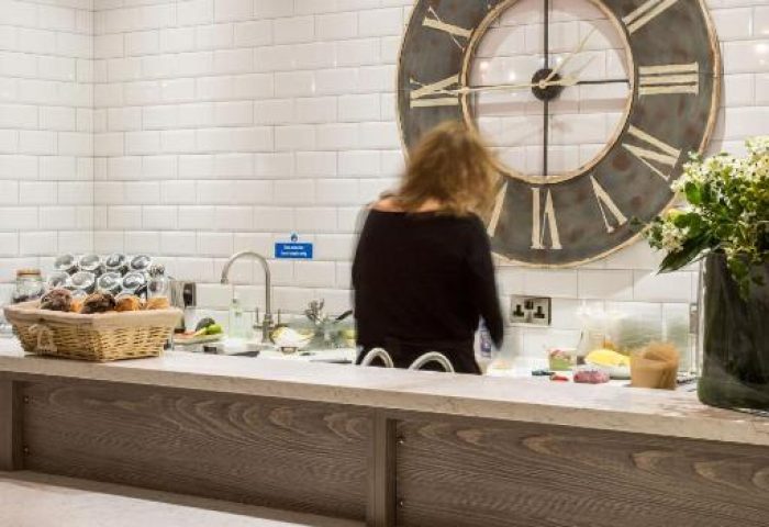 The Z Hotel City's buffet area with a large clock, pendant lights, and white brick wall. A gay-friendly hotel with modern design elements.