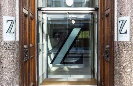 Entrance to The Z Hotel City, a gay-friendly hotel. Glass doors feature a large Z logo. Wood and stone facade. Modern design.