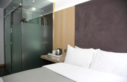 Bedroom at The Z Hotel Piccadilly, a gay-friendly hotel. Features a bed, frosted glass shower, and modern decor. Ideal for gay travel.