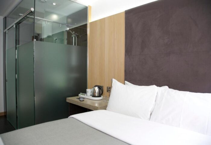 Bedroom at The Z Hotel Piccadilly, a gay-friendly hotel. Features a bed, frosted glass shower, and modern decor. Ideal for gay travel.