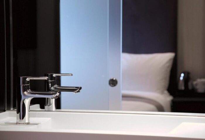Bathroom detail at The Z Hotel Shoreditch, a gay-friendly hotel. Modern sink & faucet with a glimpse of the bed. Ideal for gay travel.