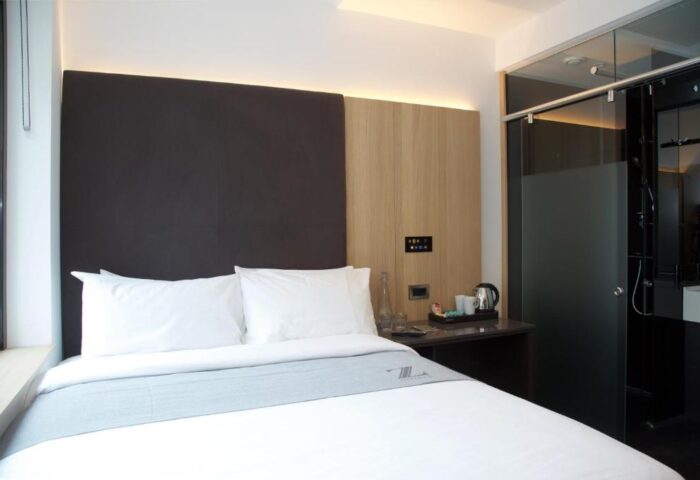 The Z Hotel Shoreditch room. Modern design, bed with white linens, dark headboard. Glass-enclosed shower. Gay-friendly hotel in Shoreditch.