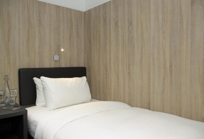The Z Hotel Shoreditch room. Single bed with white linens, black headboard, and wood paneling. Gay-friendly hotel in Shoreditch, London.