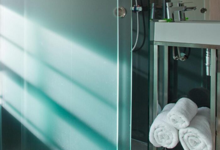 Bathroom detail at The Z Hotel Soho, a gay-friendly hotel. Shower, sink, and rolled towels. Modern design for gay men travelers.