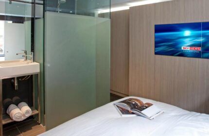 The Z Hotel Soho room: bed with a book, TV, and glass-enclosed bathroom. Modern design at this gay-friendly hotel in Soho, London.