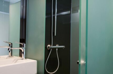 Bathroom detail at The Z Hotel Soho, a gay-friendly hotel. Features a sink, mirror, and shower with frosted glass. Modern design.
