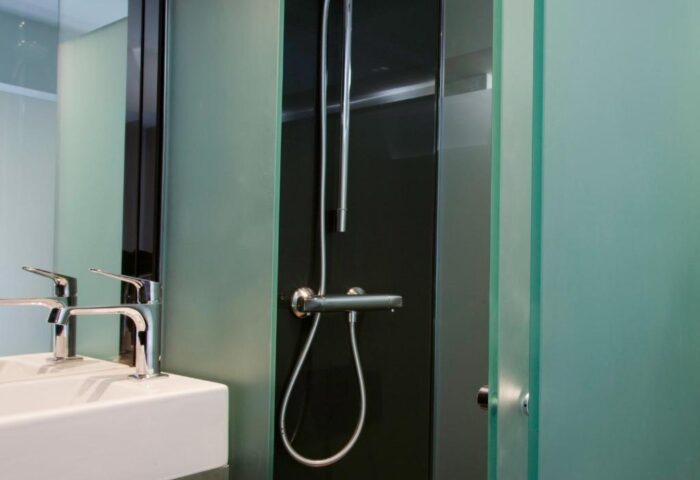 Bathroom detail at The Z Hotel Soho, a gay-friendly hotel. Features a sink, mirror, and shower with frosted glass. Modern design.