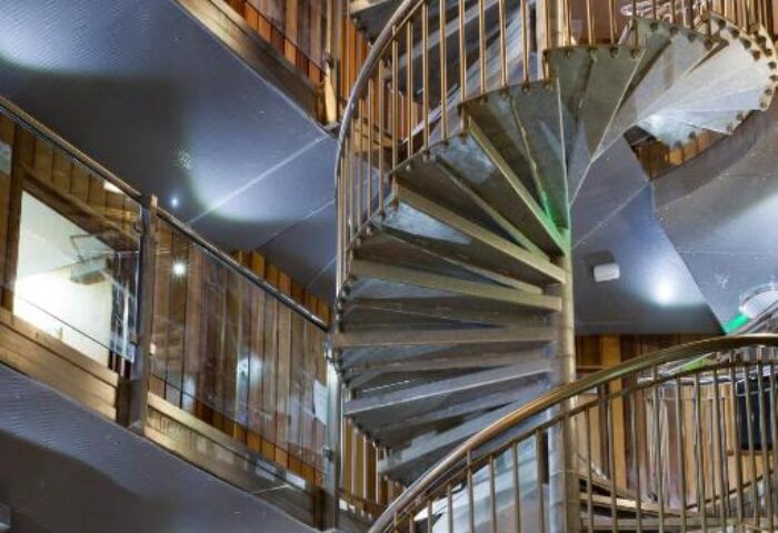 Interior of The Z Hotel Soho, a gay-friendly hotel. Features a spiral staircase with metal railings and wooden walls. Modern design.