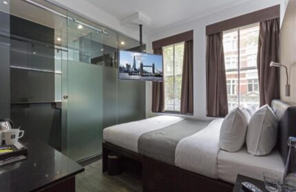 The Z Hotel Soho room. Gay-friendly hotel with a double bed, TV showing the Tower Bridge, and a frosted glass bathroom. Modern, comfortable stay.