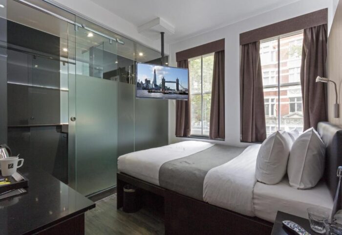 The Z Hotel Soho room. Gay-friendly hotel with a double bed, TV showing the Tower Bridge, and a frosted glass bathroom. Modern, comfortable stay.