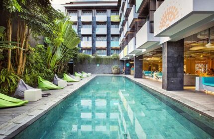 Pool view at Tijili Hotel Seminyak, a gay-friendly hotel. Beanbags line the pool deck. Tropical plants add to the relaxing vibe. Seminyak hotel.