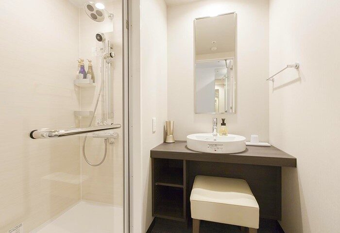 Tokyu Stay Shinjuku bathroom. Shower, sink, mirror, and stool. Modern design in this gay-friendly hotel in Shinjuku, Tokyo.