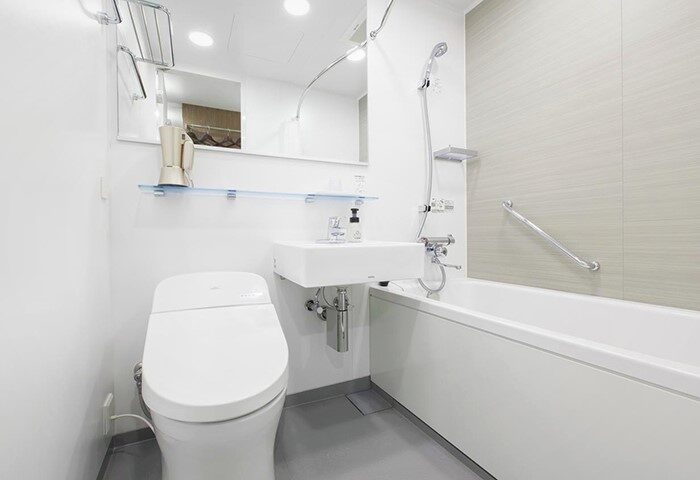 Tokyu Stay Shinjuku gay-friendly hotel bathroom. Features a toilet, sink, mirror, and bathtub with a shower. Clean, modern design for gay travelers.