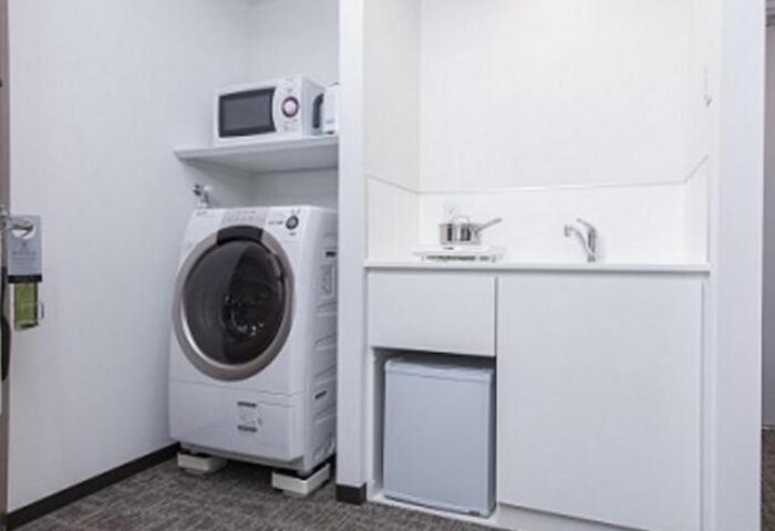 Tokyu Stay Shinjuku gay-friendly hotel room. Features include a microwave, washing machine, mini-fridge, and sink for convenience.