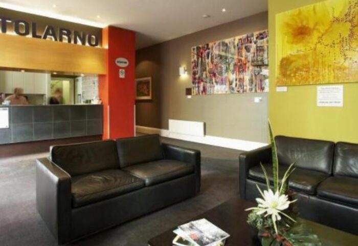 Tolarno Hotel lobby area. Gay-friendly hotel with modern decor, black leather sofas, and artwork. A welcoming space for gay travelers.